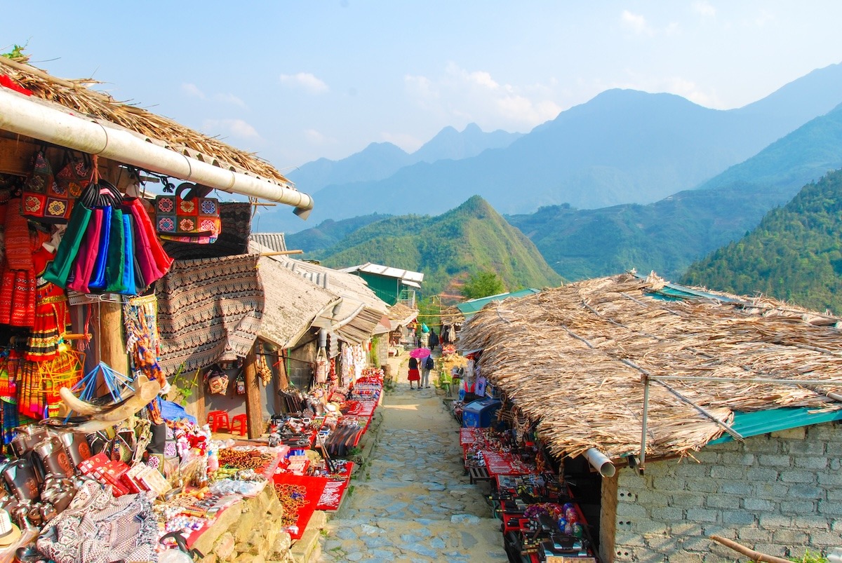 H'mong minority village in Sapa — traditional wooden stilt houses surrounded by terraced fields